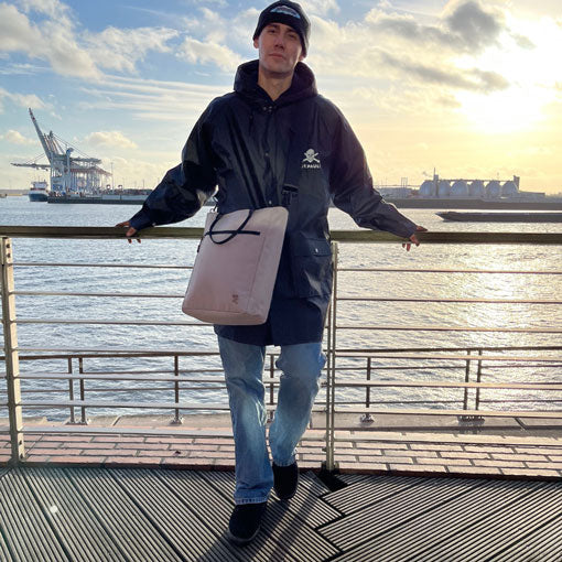 Mann traegt die FUCHS und REBELL JONA Umhaengetasche in beige als Cross-Body-Tasche