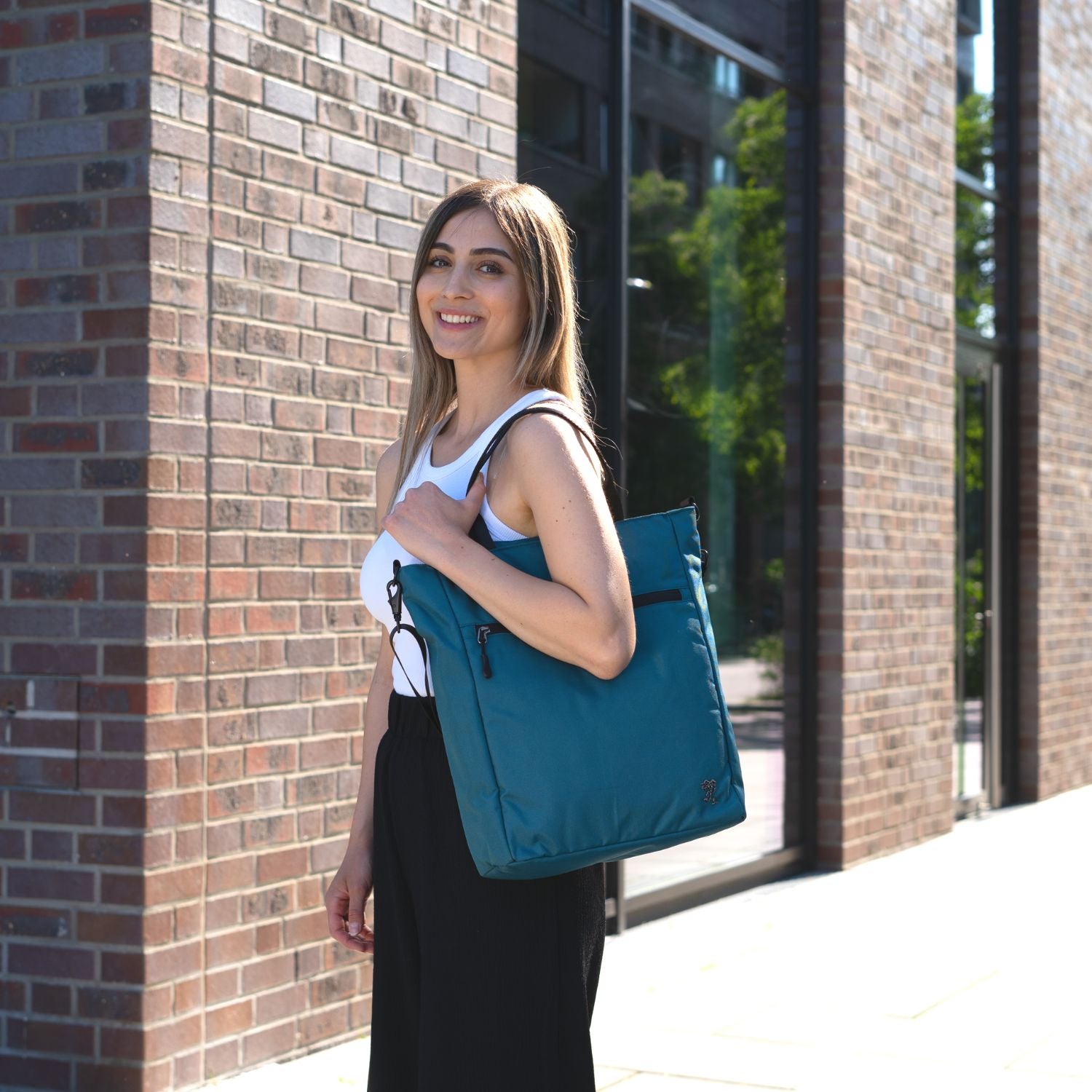 Junge Frau traegt die FUCHS und REBELL JONA Umhaengetasche in petrolblau