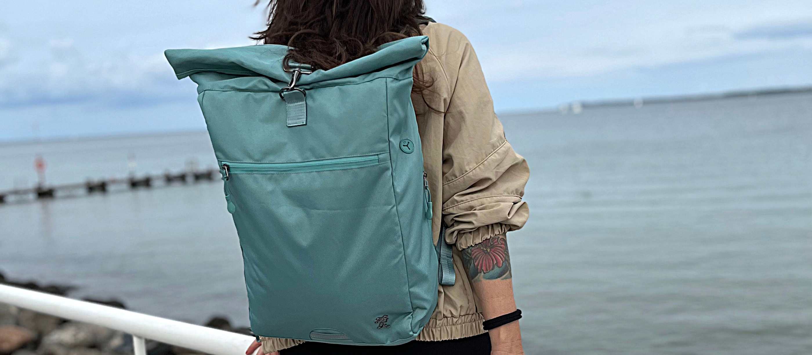 Frau mit dem FUCHS und REBELL PIET Rolltop Rucksack in mint blau und Kind am Strand