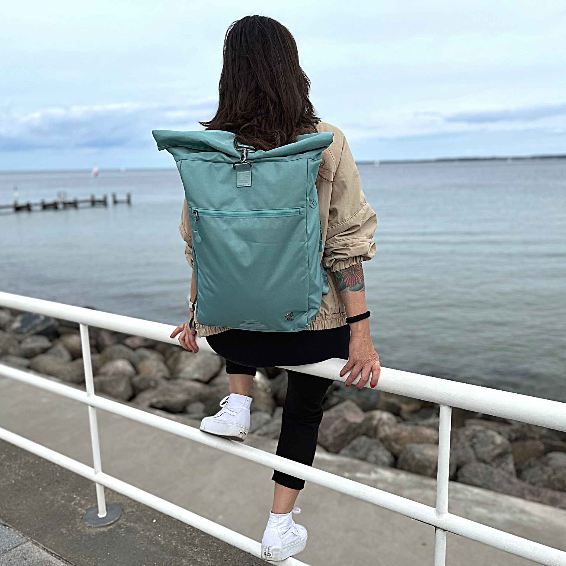 Frau traegt den FUCHS und REBELL PIET Rolltop Rucksack in mint blau. 