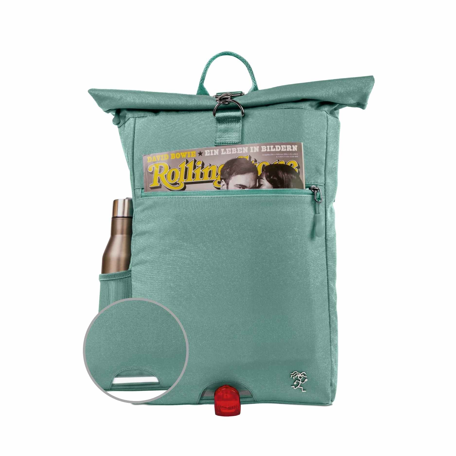 Vorderansicht des bepackten FUCHS und REBELL PIET Rolltop Rucksacks in mint blau mit Thermoflasche, Magazin und reflektierendem Riemen auf der Vorderseite.