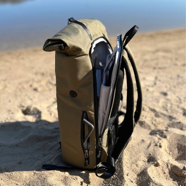 Seotenansicht von dem FUCHS und REBELL Rolltop Rucksack PIET in gruen am Strand.