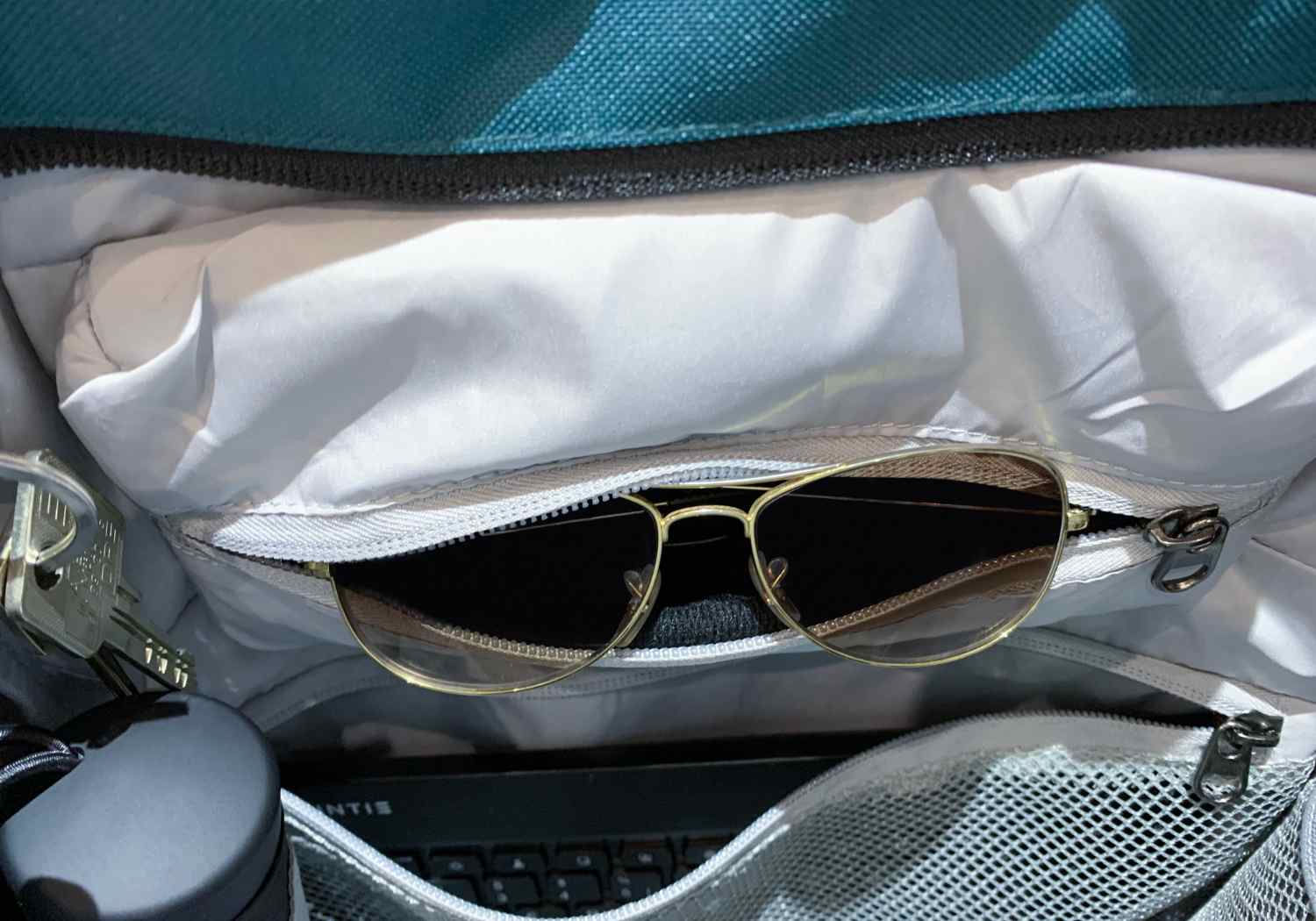 Innenansicht von der vollgepackten FUCHS und REBELL Umhaengetasche JONA in petrolblau. Das Foto zeigt vor allem das gepolsterte Brillenfach im Innenbereich der Umhaengetasche. 