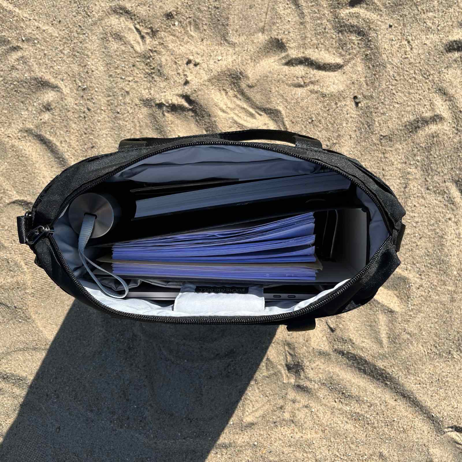 Innenansicht von der FUCHS und REBELL JONA Umhaengetasche in schwarz am Strand. 
