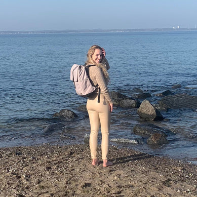 Junge Frau spaziert am Strand mit dem beige MATS Daypack Rucksack.