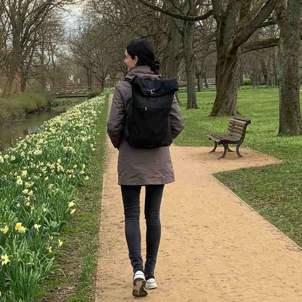 Gutaussehende Frau geht mit dem schwarzen PIET Rolltop Rucksack in Berlin spazieren.